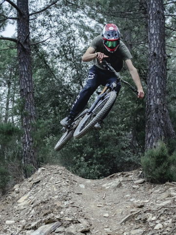 man riding mountain bike ramping on forest